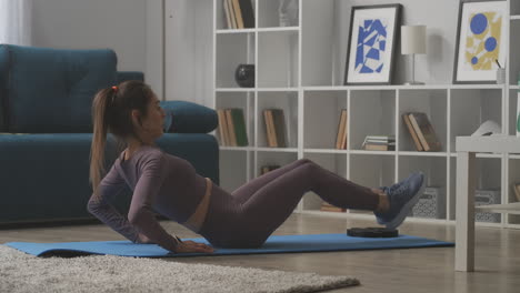 sporty-woman-is-doing-crunches-on-floor-in-living-room-of-modern-apartment-training-home-at-quarantine-healthy-lifestyle-and-sport-activities